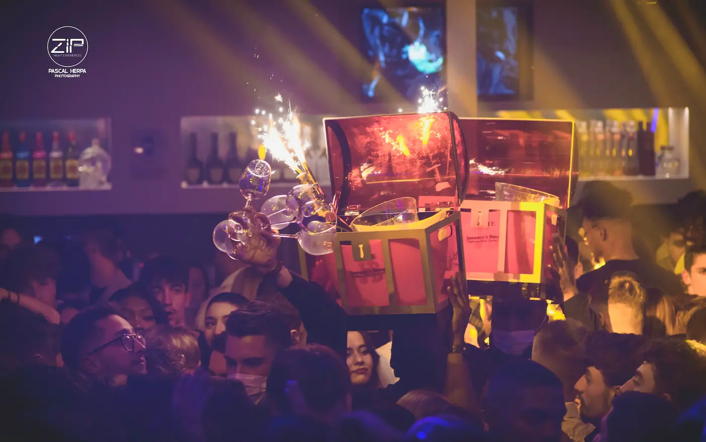 Coffrets de bouteilles portés en salle avec fontaines à étincelles au Zip Club